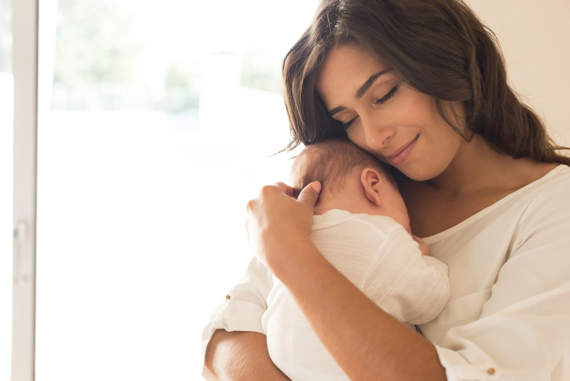 Una mamma abbraccia con dolcezza il proprio neonato