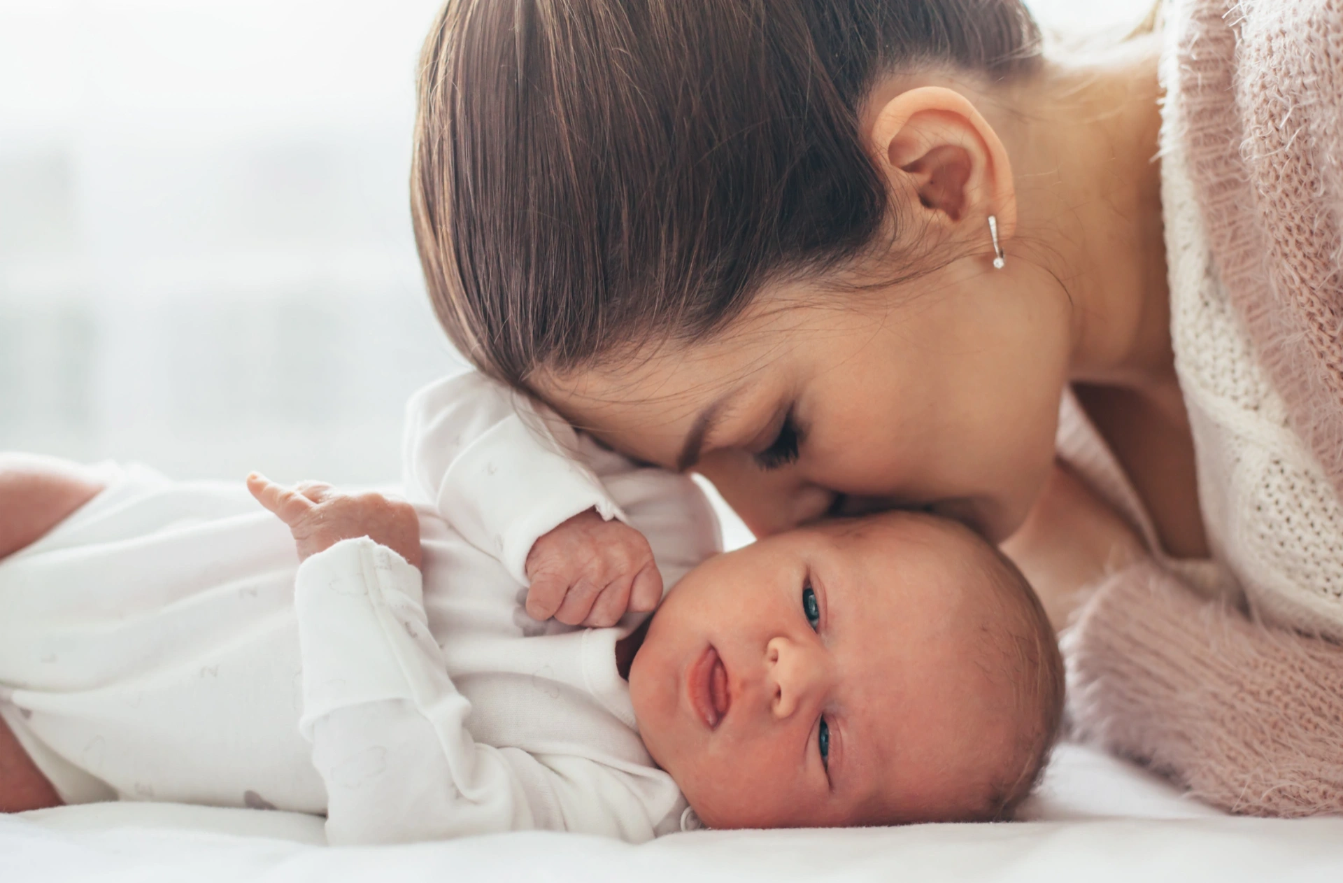 Una mamma osserva con dolcezza il proprio neonato sdraiato accanto